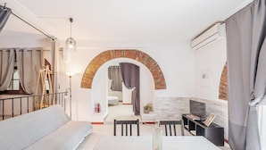 Una habitación moderna con sofá, mesa de comedor, televisor y un arco de ladrillo.