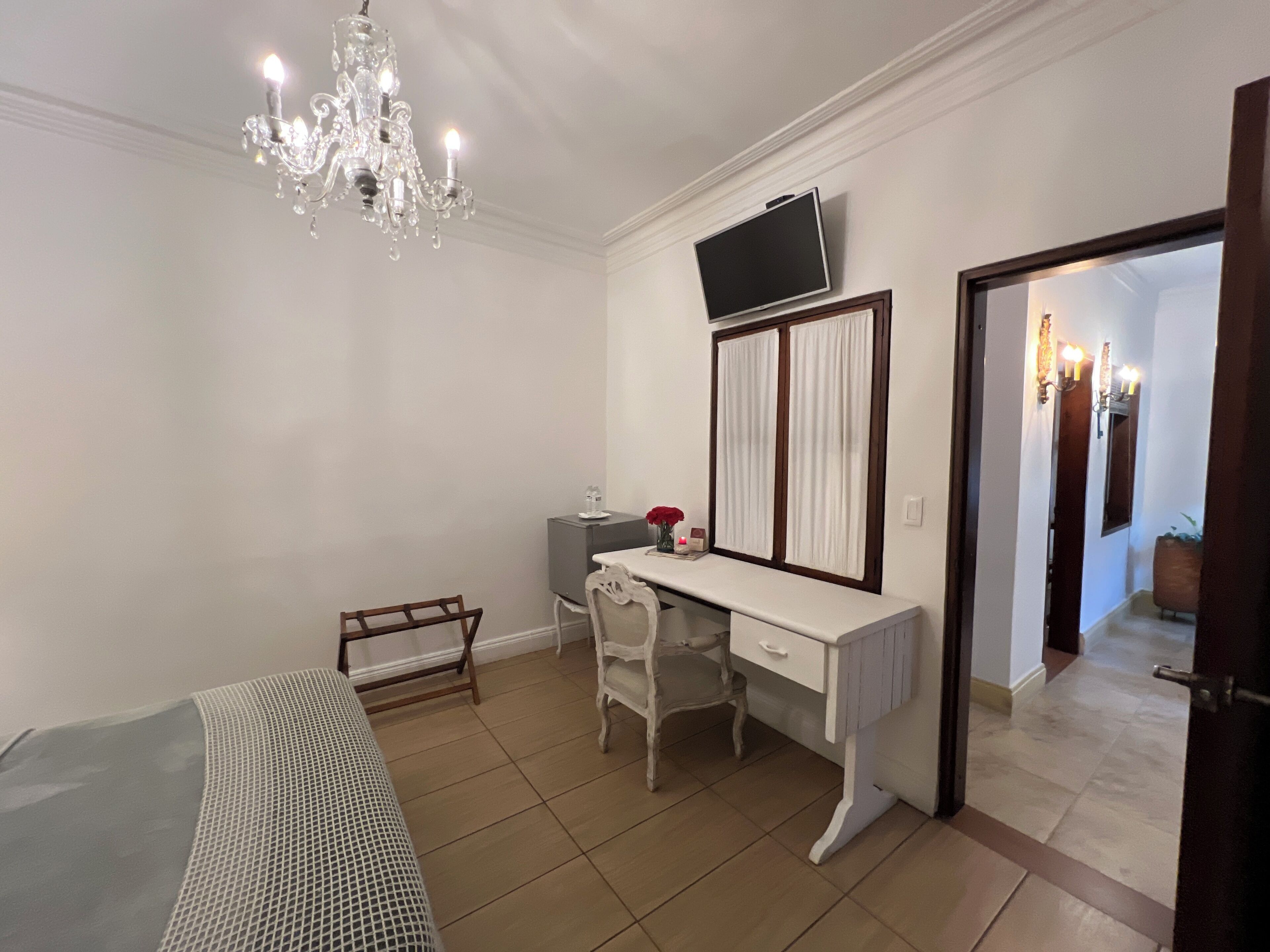 Un dormitorio con cama, escritorio, televisor y candelabro.