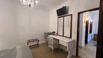 Un dormitorio con cama, escritorio, televisor y candelabro.