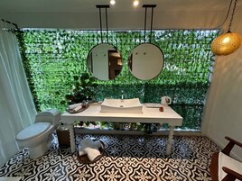 Un baño con un lavabo blanco, dos espejos redondos, un inodoro y baldosas de suelo estampadas.