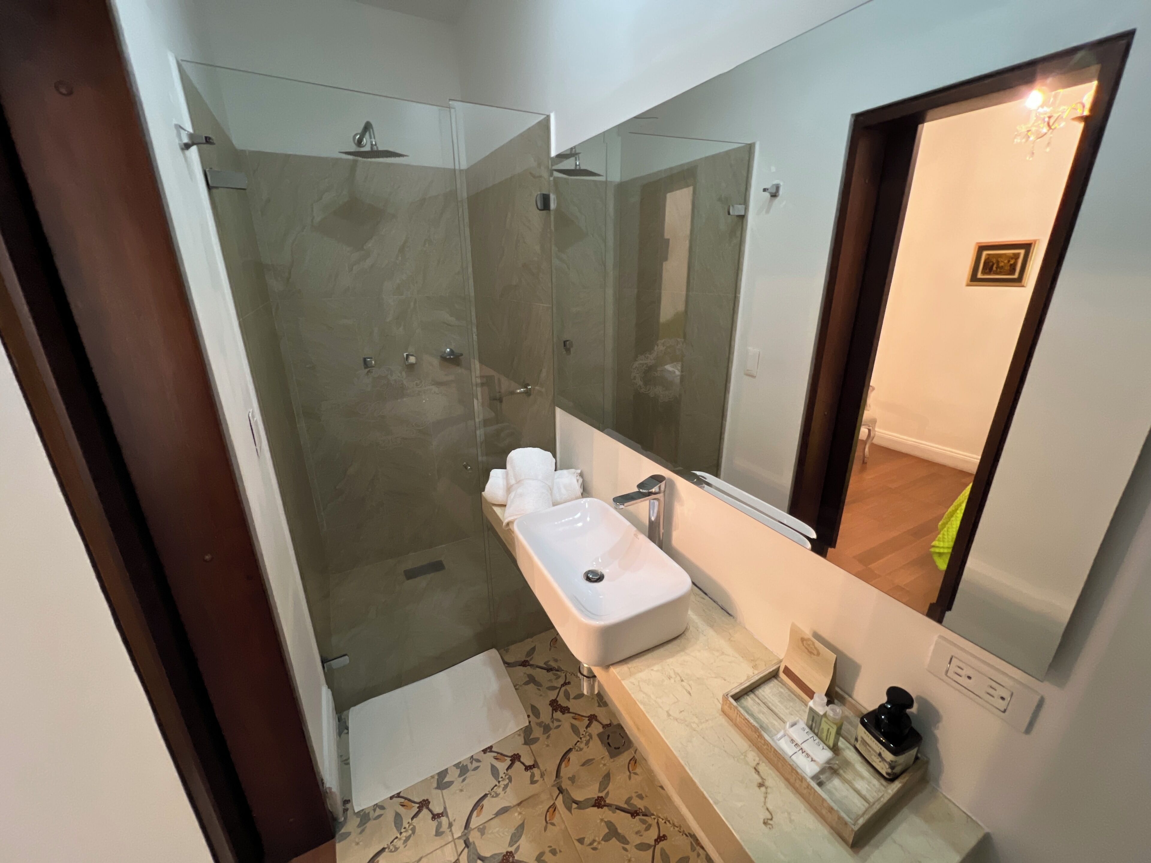 Une salle de bain avec une douche à parois de verre, un lavabo et un miroir.