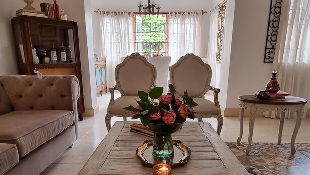 A living room with a wooden coffee table, two armchairs, a sofa, and a decorative vase with flowers. - Leclerc Hotel Boutique Granada (Cali)