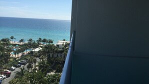 En vy över ett strandhotell med en pool, palmer och ett klart, blått hav.