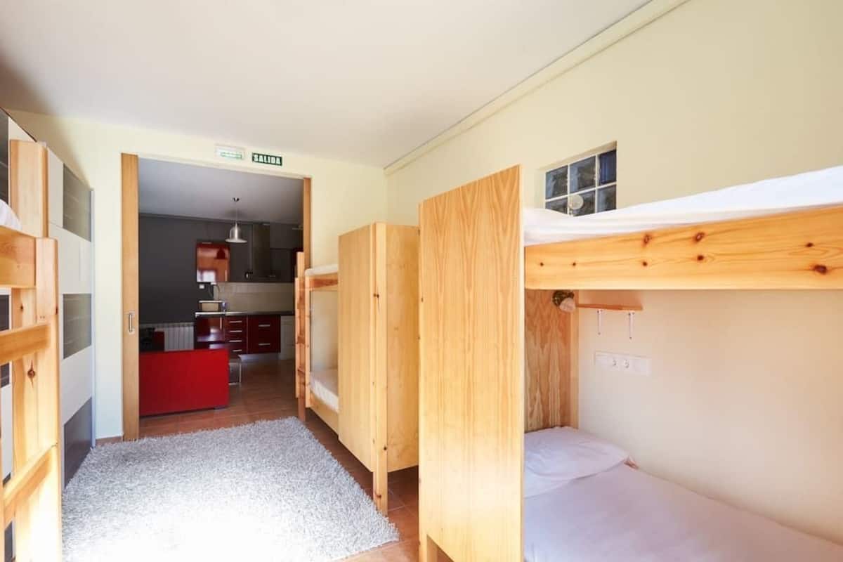 A compact room with bunk beds, a kitchenette, and a small window.