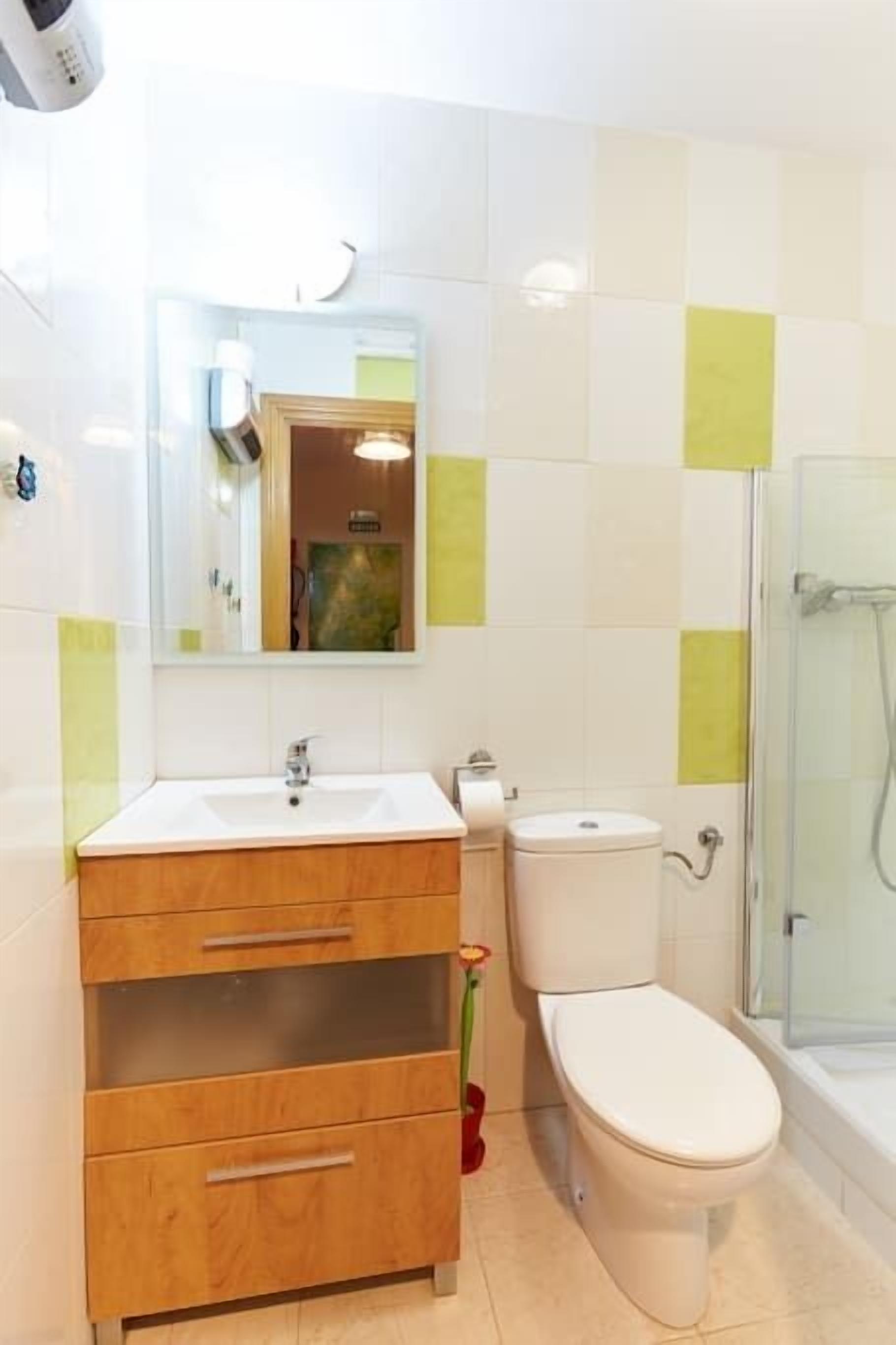 Un baño con tocador de madera, inodoro y cabina de ducha de vidrio.