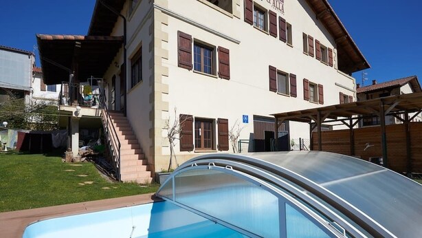 A two-story building with a swimming pool in front. - Alojamientos Acá y Allá - Hostel (Esteribar)