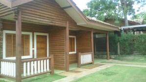 Eine Holzhütte mit Veranda, überdachtem Bereich und gepflegtem Rasen.