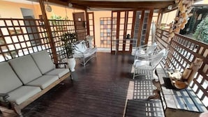 An outdoor deck with a wooden floor, a sofa, and a table with chairs. - Pousada Água da Fonte (Florianópolis)