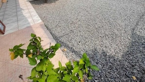 A courtyard with a gravel ground, potted plants, and a building with a balcony. - Pousada Água da Fonte (Florianópolis)