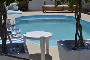 Una piscina al aire libre, sillones reclinables de piscina