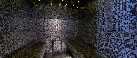 Une pièce dont le mur et le plafond sont recouverts de mosaïques, avec un banc et une petite fenêtre.
