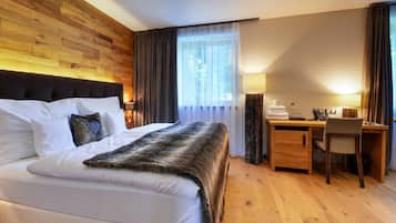 Habitación de hotel con una cama grande, cabecera de madera, escritorio con silla y ventana con cortinas.