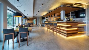 Un restaurante moderno con barra, muebles de madera e iluminación colgante.