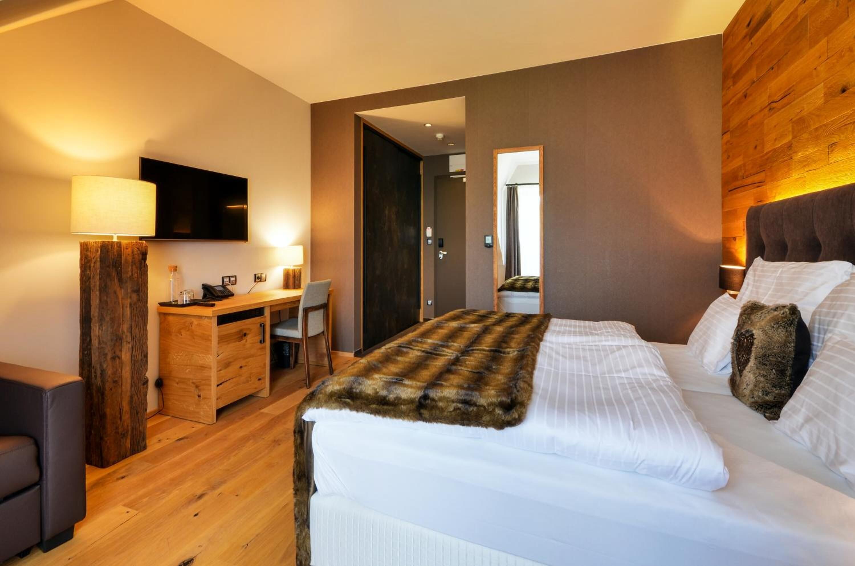 A modern hotel room with a large bed, a desk, and a chair.