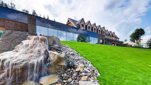 Un edificio moderno con una cascada y un césped bien cuidado.