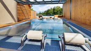 Un área de piscina con sillas de descanso y una pérgola.