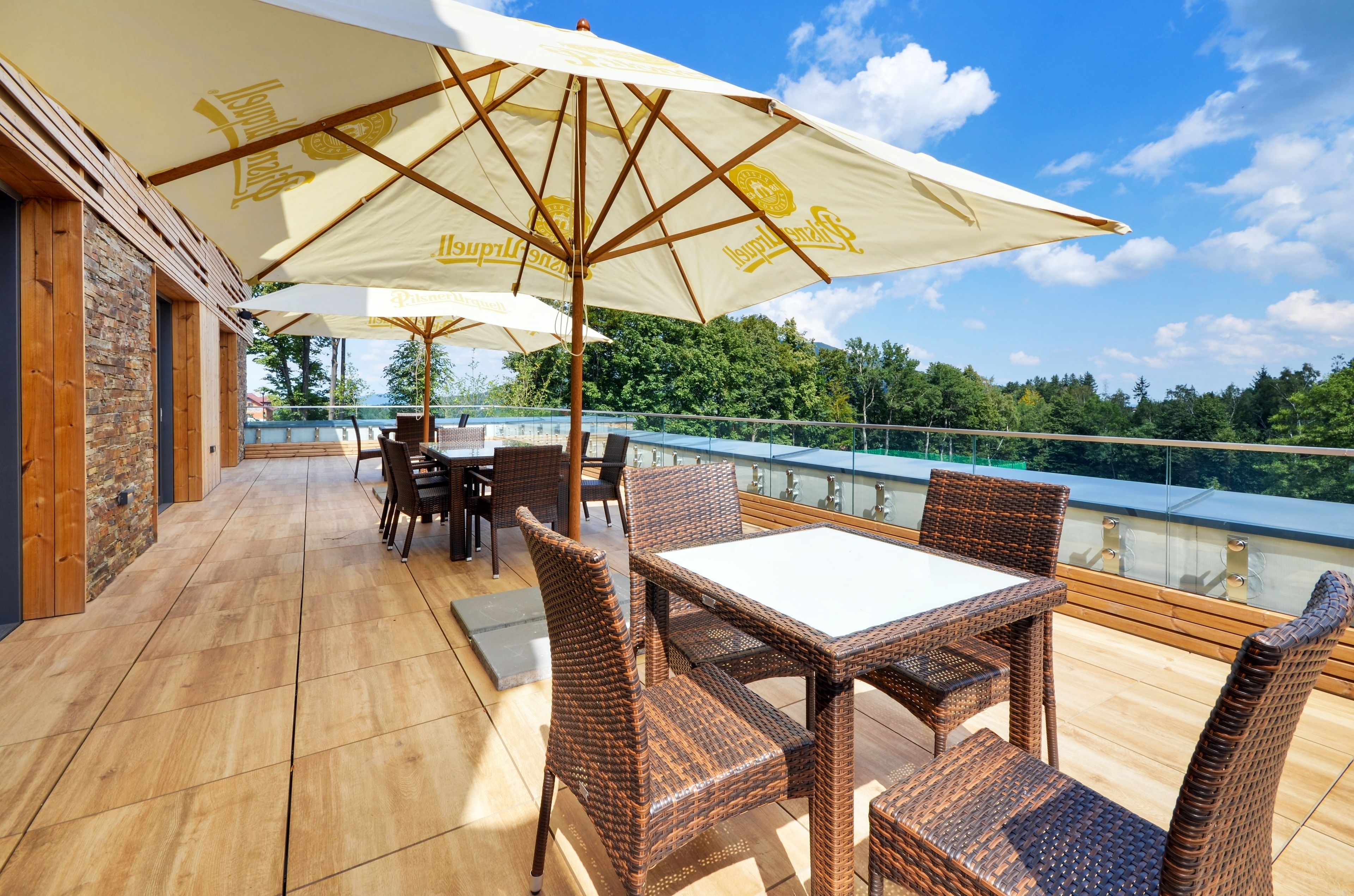 Une terrasse extérieure aménagée avec des meubles en osier et des parasols, offrant une vue panoramique.