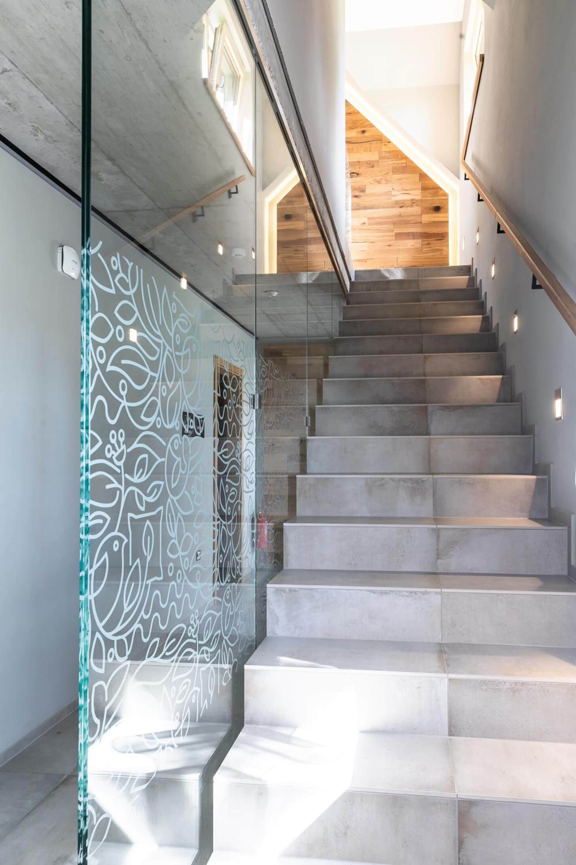 A modern staircase with glass railings and a wooden ceiling.