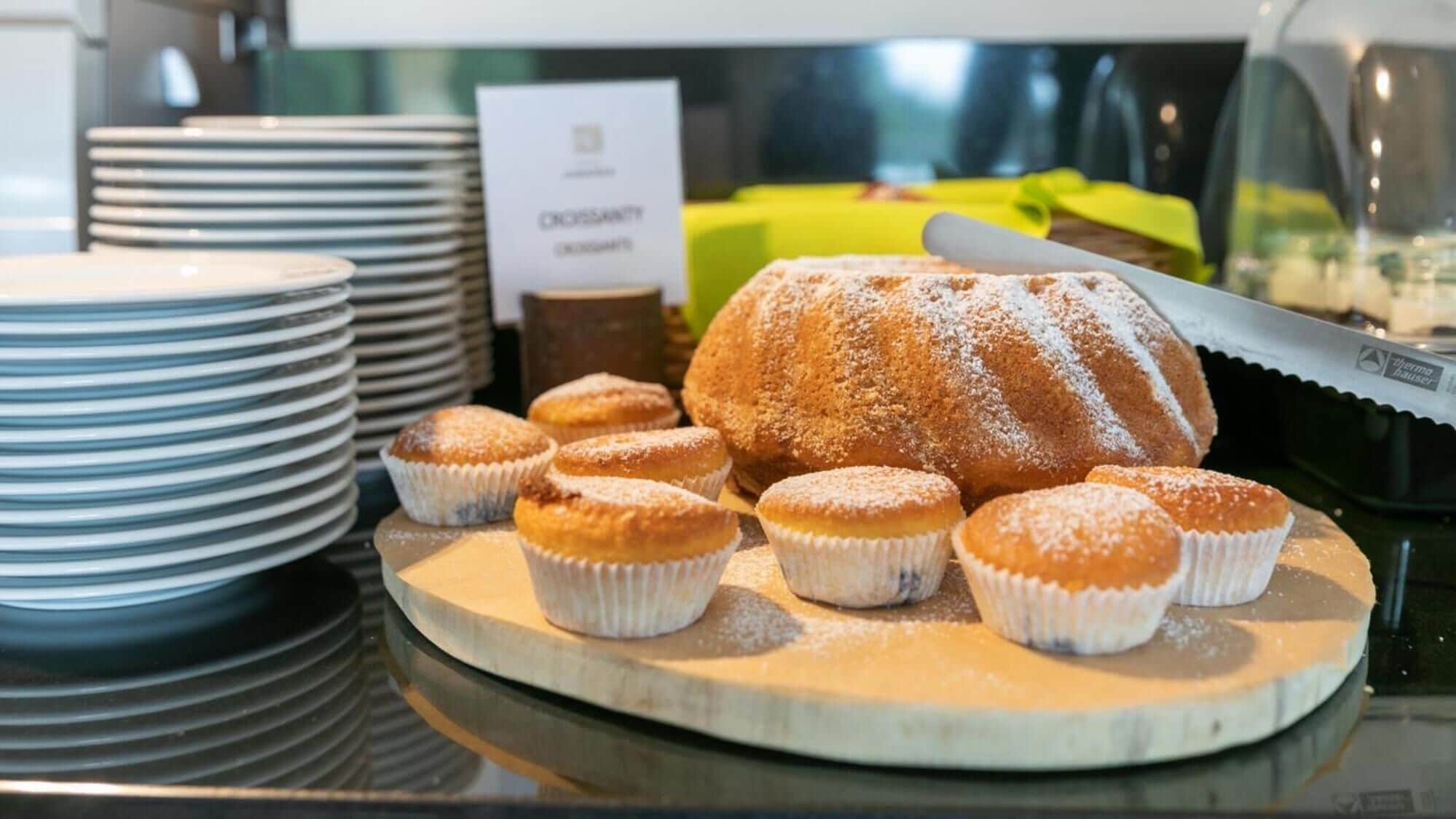 Una presentación de pasteles que incluye un pastel nordés y muffins sobre una tabla de madera.