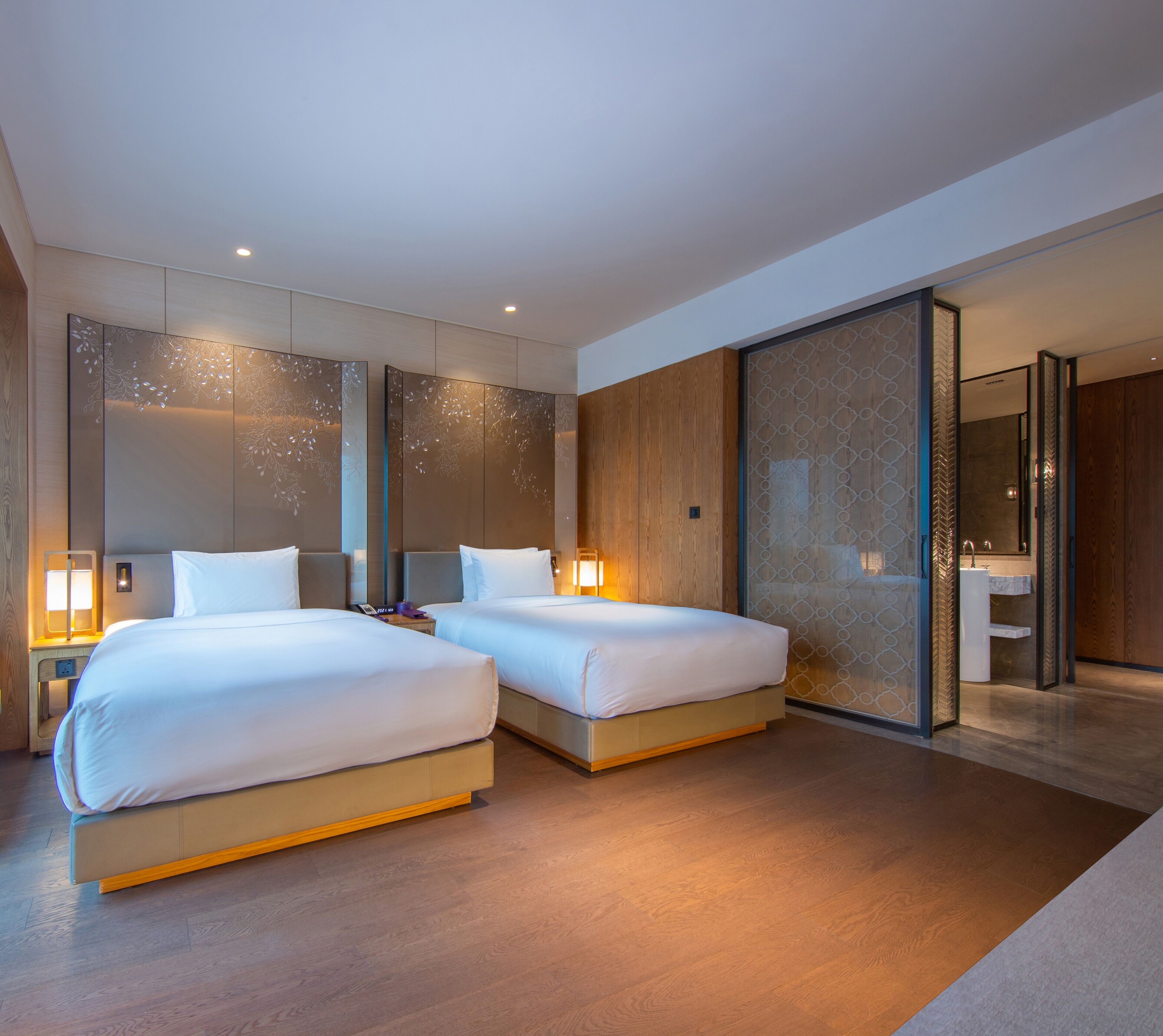 Habitación de hotel moderna con dos camas, un espejo grande y vistas al baño.