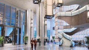 A spacious lobby with a modern staircase and a glass elevator.
