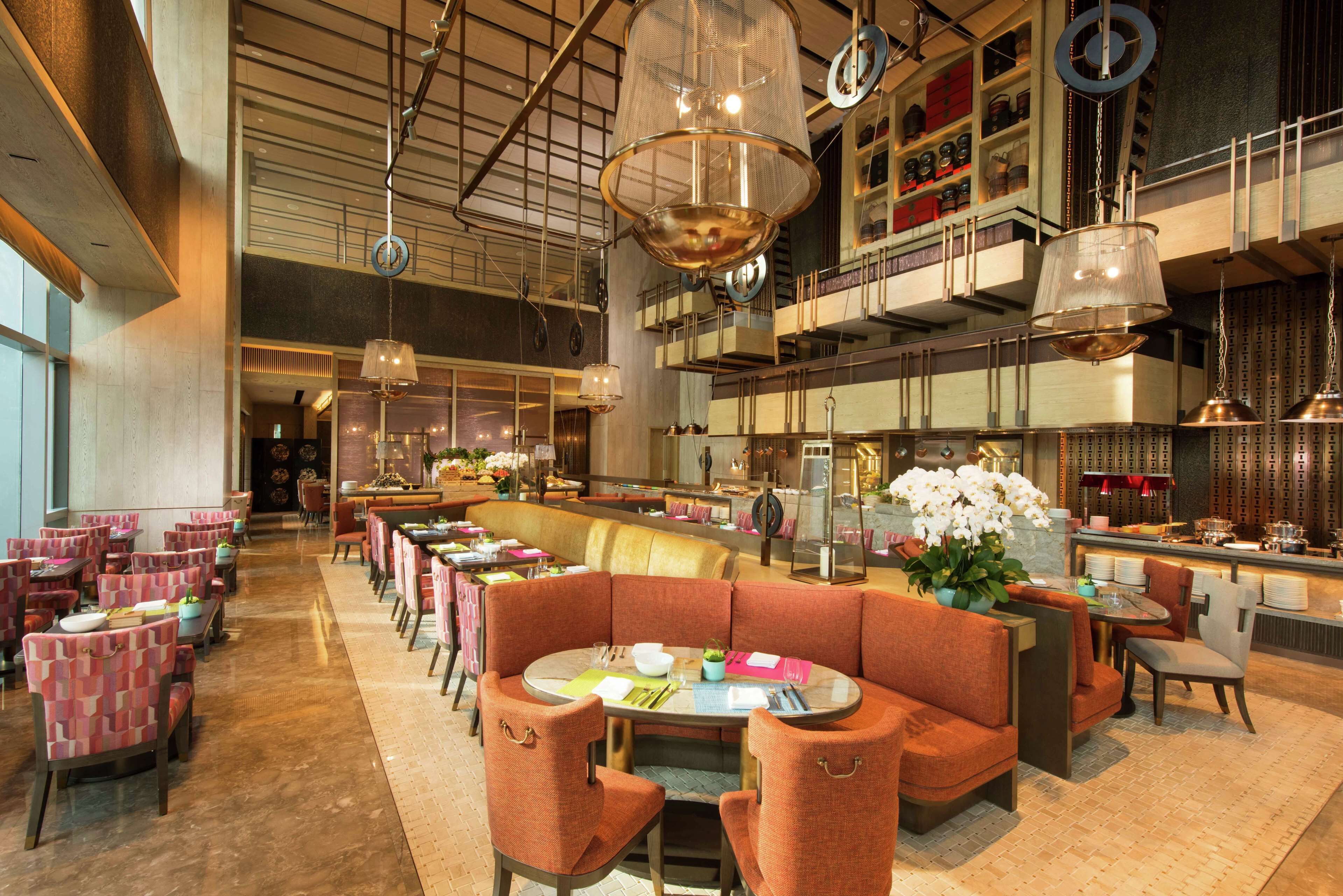 Un restaurant spacieux avec de hauts plafonds, plusieurs espaces de restauration et un éclairage moderne.