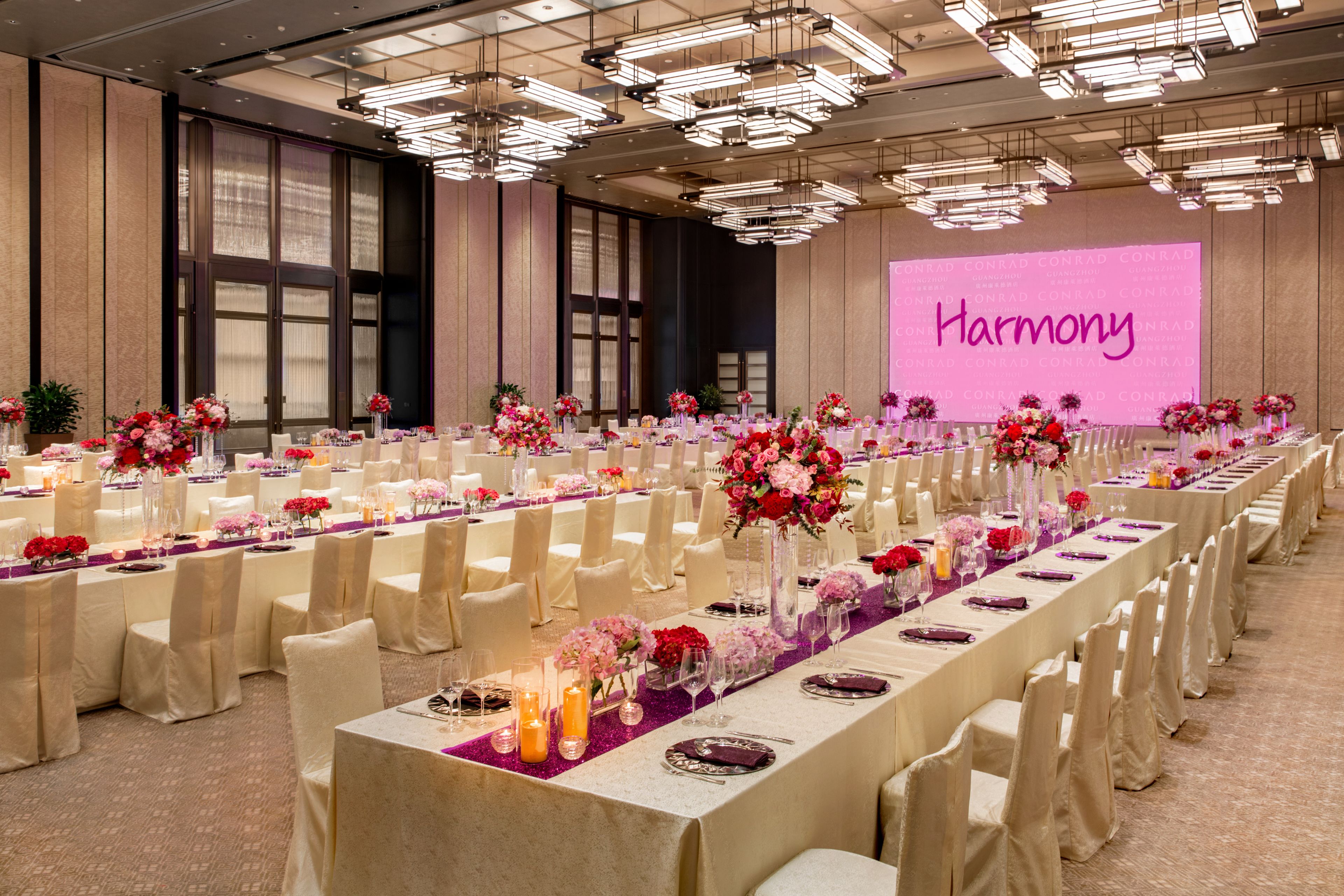 A banquet hall with long tables set for a formal event, featuring floral centerpieces and elegant table settings.