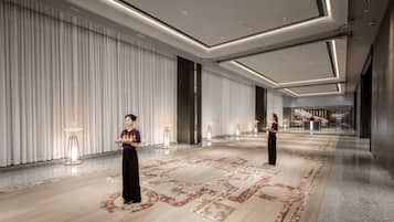 A spacious, modern hotel lobby with a long corridor, elegant lighting, and a patterned floor.