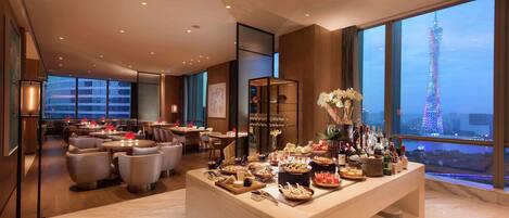 Een hotel lobby met een buffet, zithoek en uitzicht op een toren.