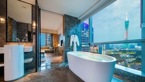 A modern bathroom with a large bathtub, two sinks, and a view of a cityscape including a tall tower. - Conrad Guangzhou (Guangzhou)