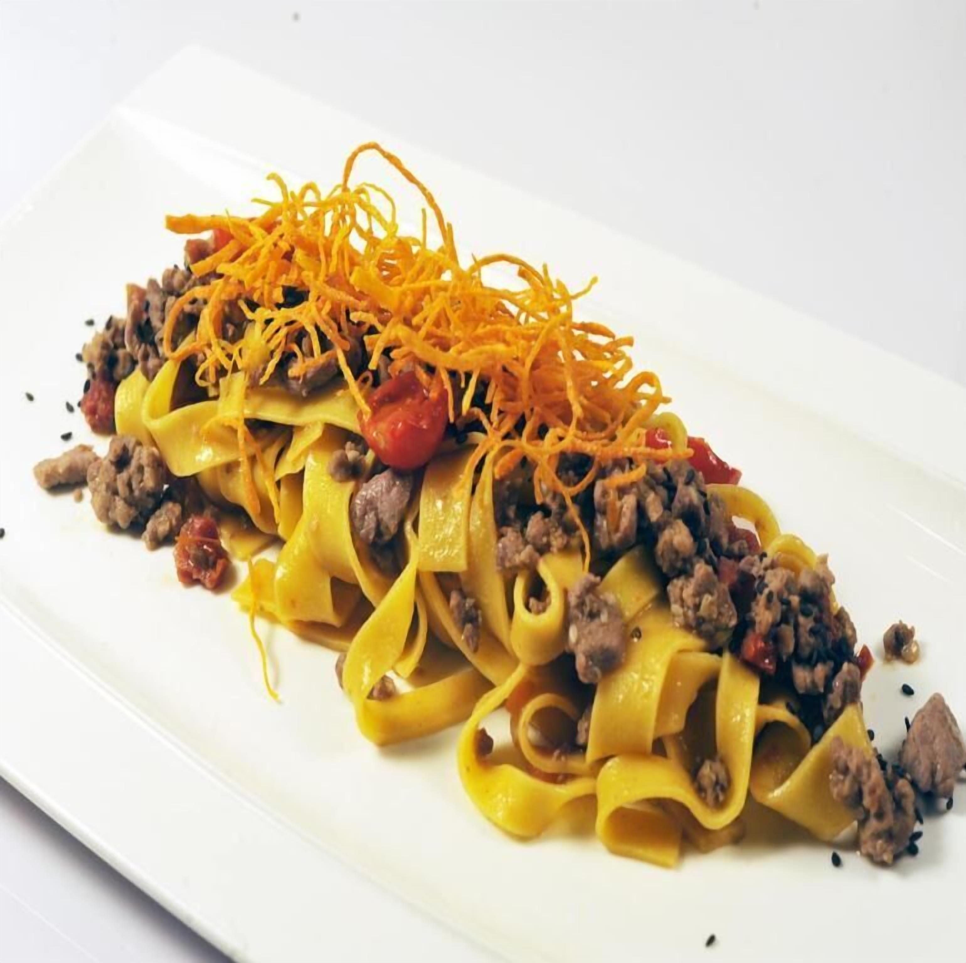Een bord pasta met gehakt, tomaten en geraspte kaas.