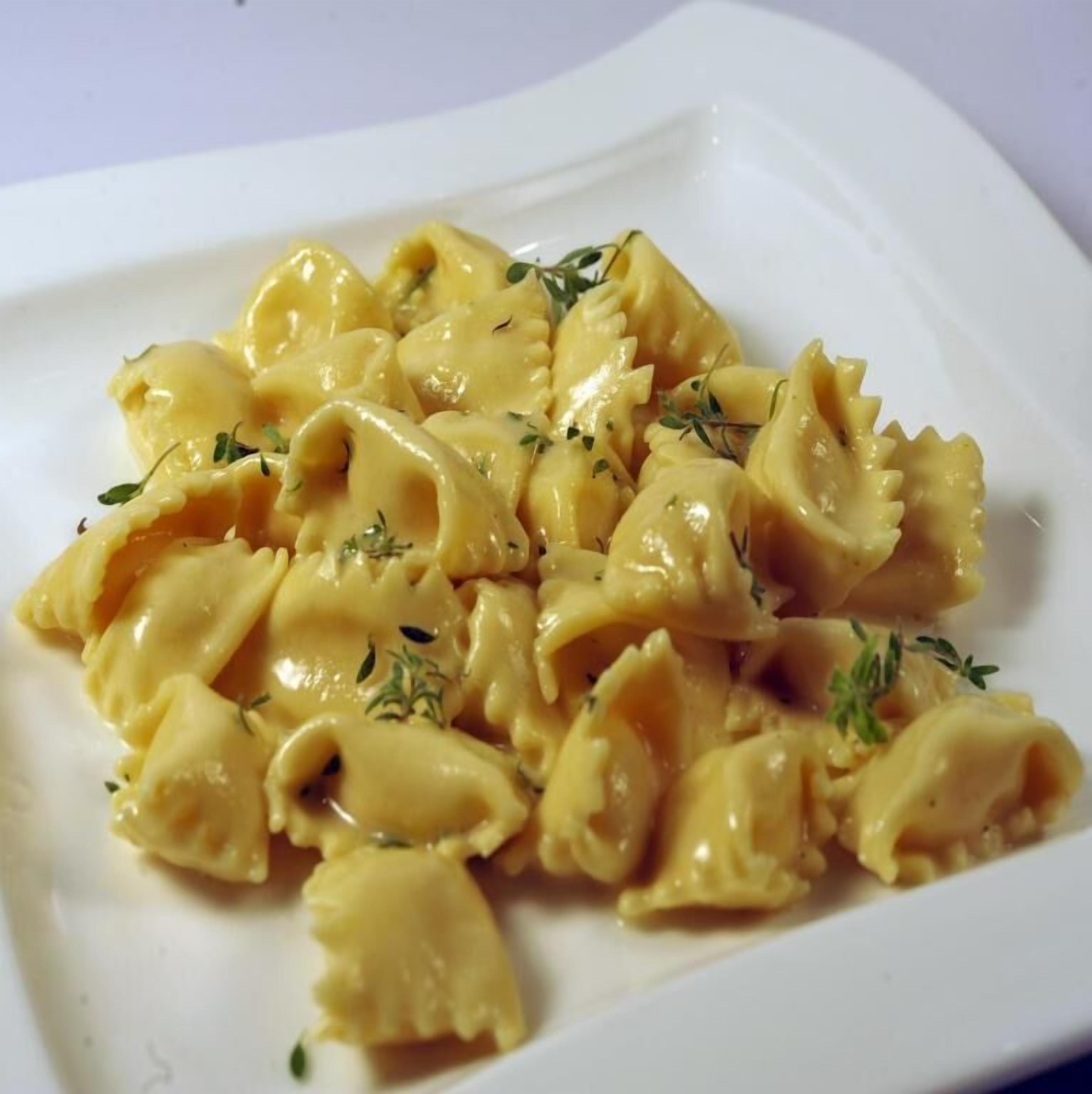 Een bord ravioli pasta met een romige saus, versierd met kruiden.