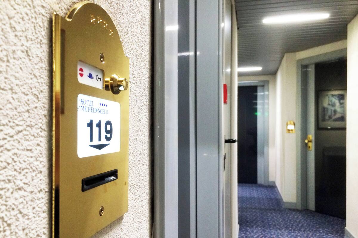 Une porte de chambre d’hôtel avec une plaque en laiton portant le numéro « 119 » et un trou de serrure.