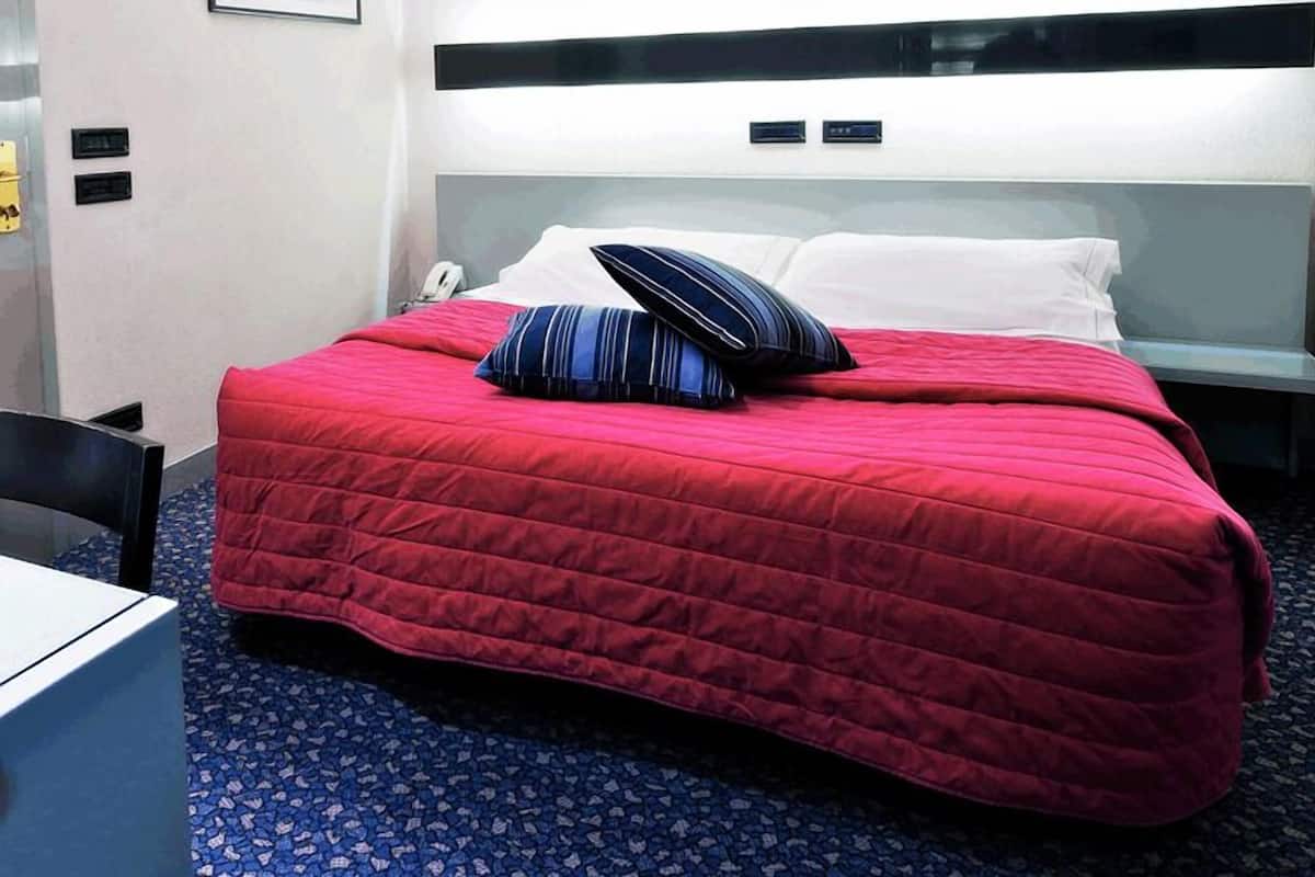 Une chambre d’hôtel avec un grand lit, une table de chevet et une chaise.