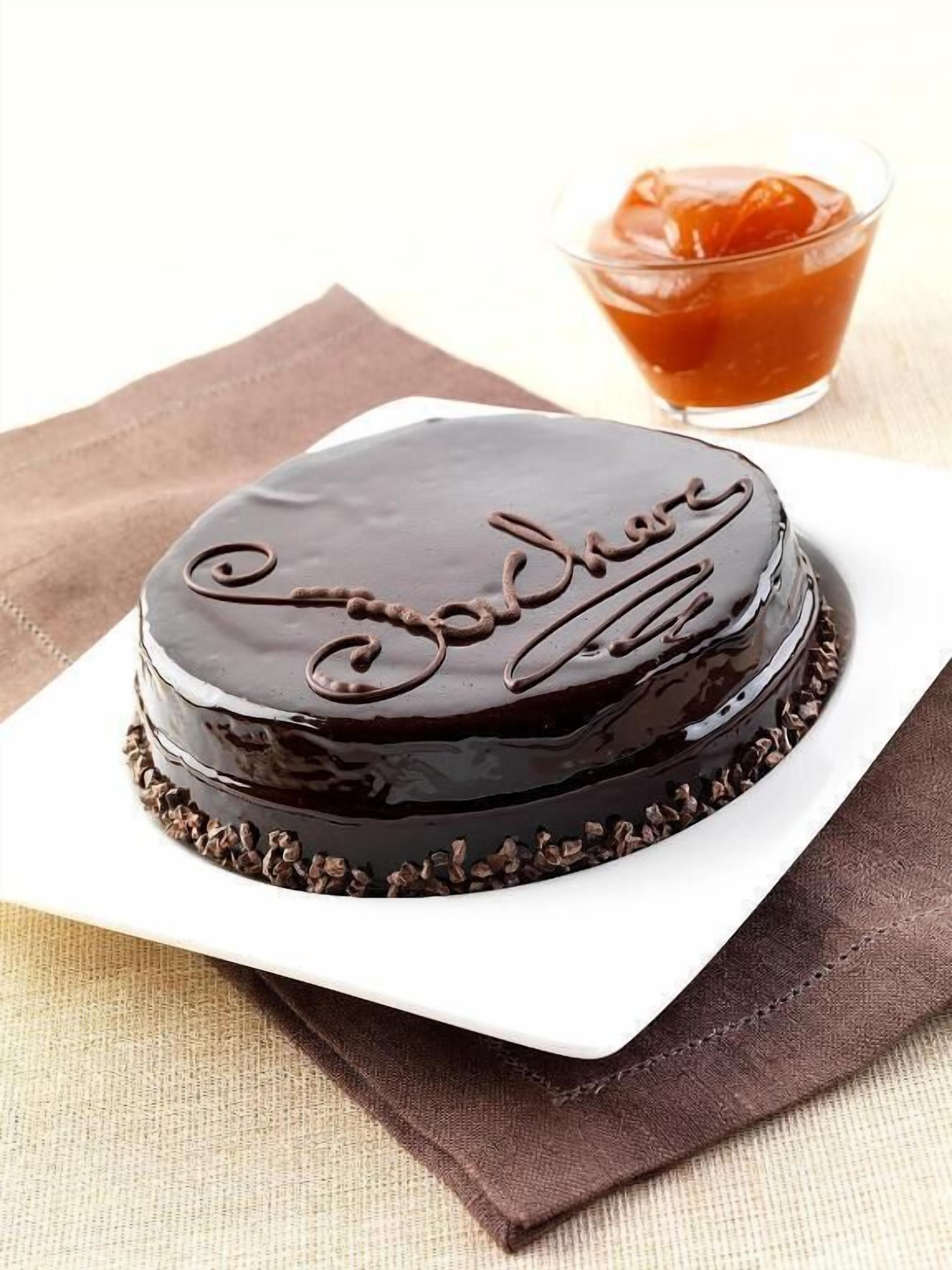 A chocolate cake with "Soda" written on it, placed on a white plate with a brown napkin underneath.