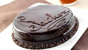 A chocolate cake with "Soda" written on it, placed on a white plate with a brown napkin underneath.