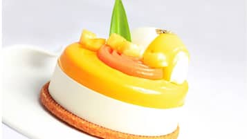 A dessert with a white base, yellow topping, and pineapple pieces, served on a round, toasted base.