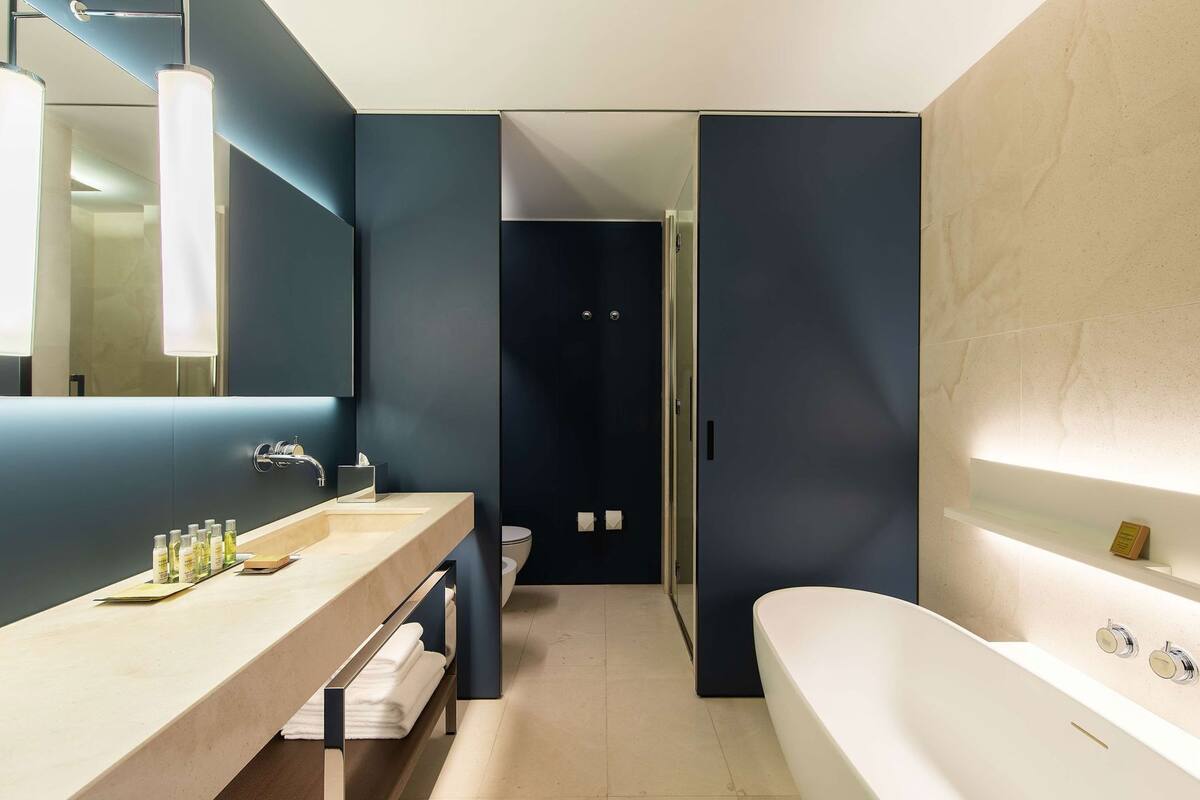Une salle de bain moderne dotée d’une grande baignoire, d’un meuble-lavabo avec miroir et d’un espace douche.