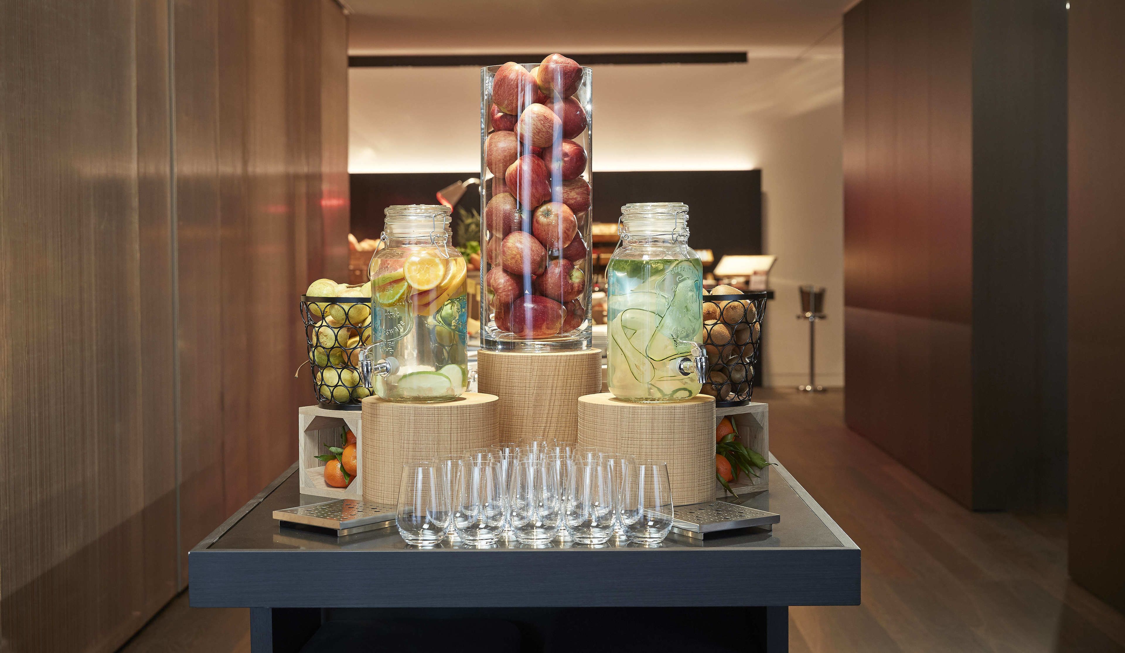 Une table sur laquelle on trouve divers récipients en verre remplis de fruits, ainsi qu’une rangée de verres vides.