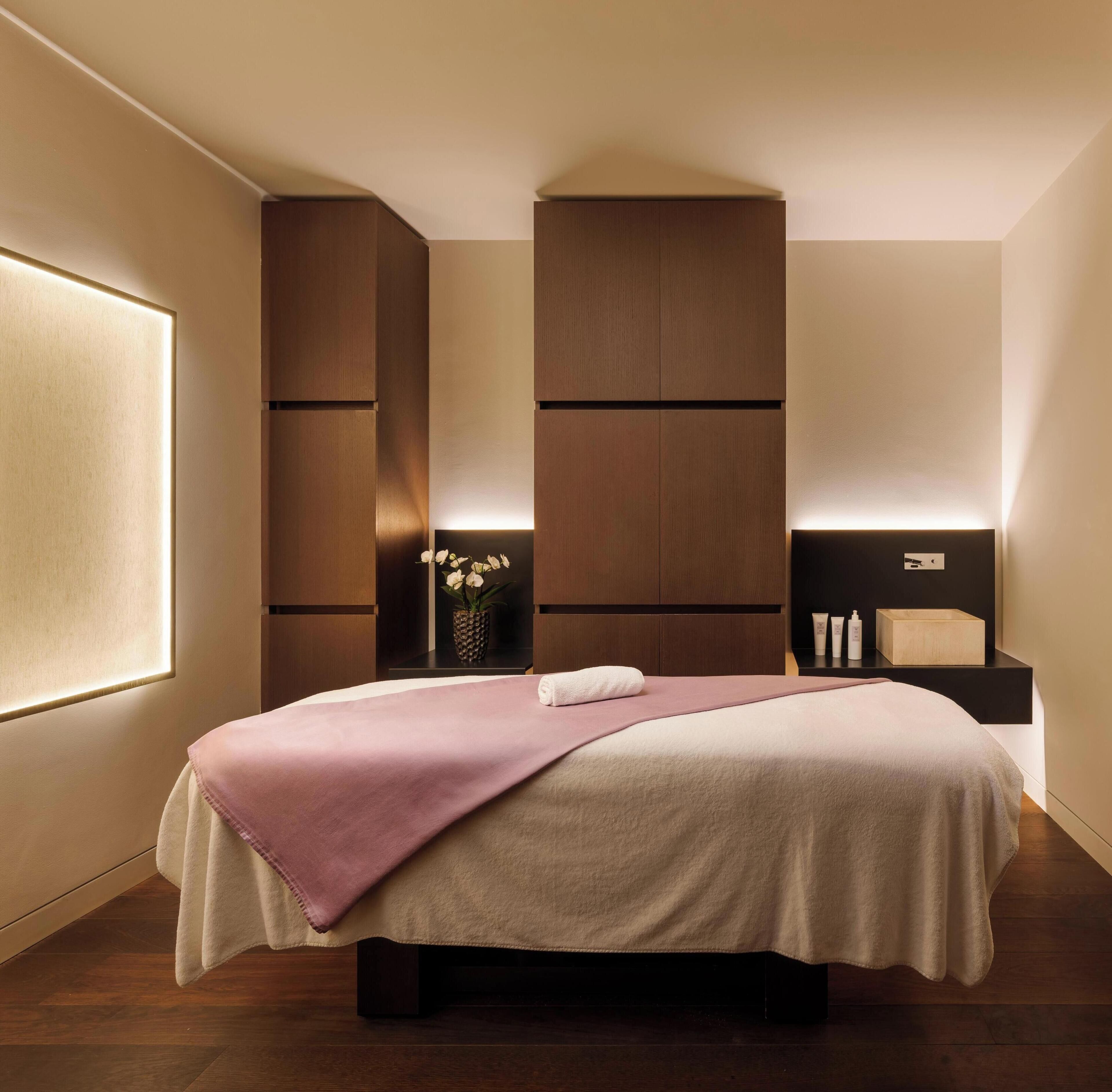 A modern bedroom with a large bed, built-in wooden headboard, bedside tables, and a window.