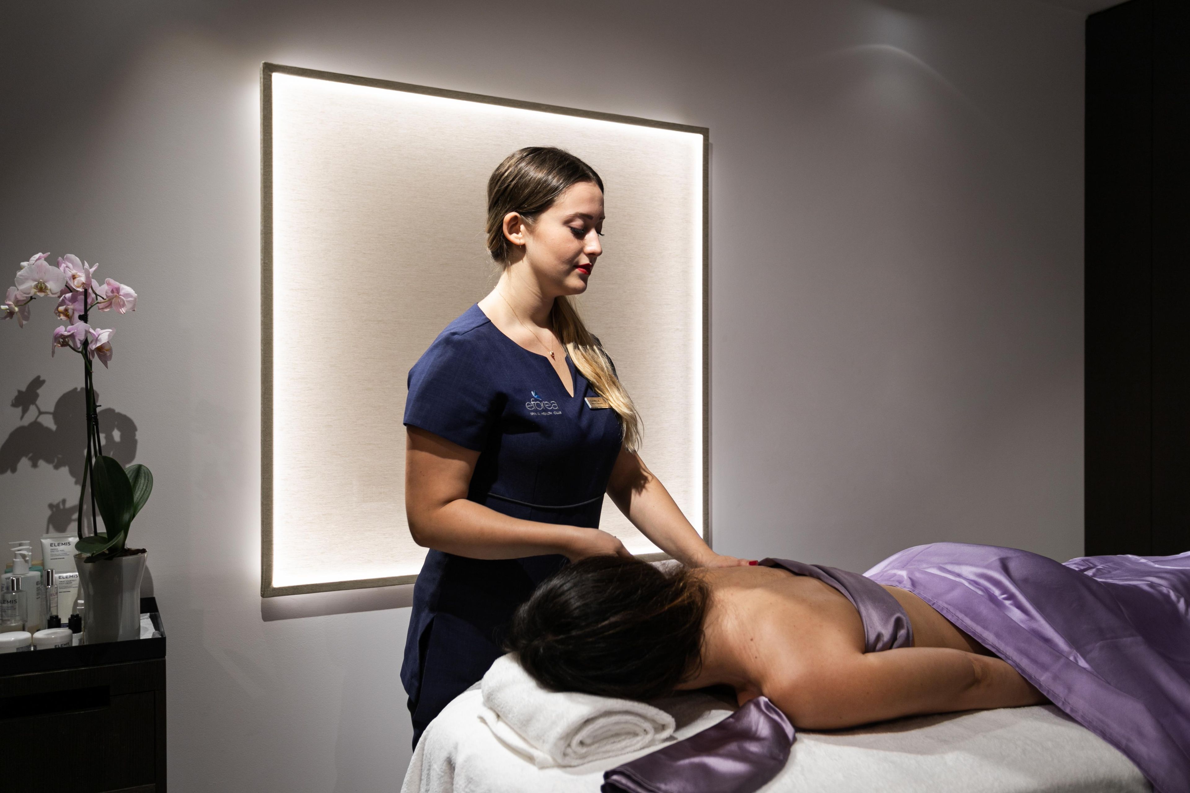 A massage therapy session in a spa room with a massage table, a client, and a therapist.
