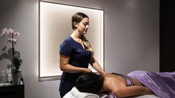 A massage therapy session in a spa room with a massage table, a client, and a therapist.
