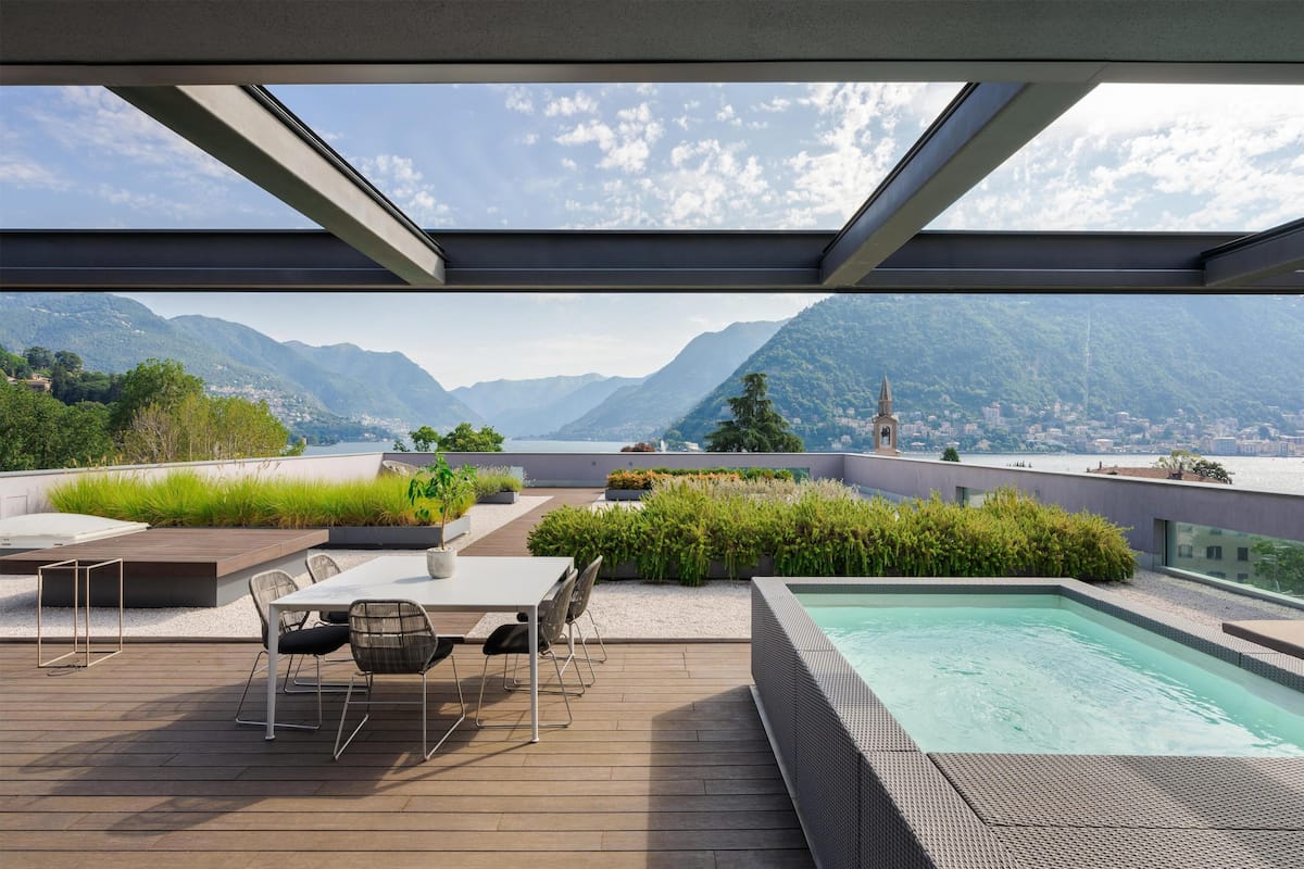 Une terrasse sur le toit avec une piscine, un espace salon et une vue sur les montagnes.
