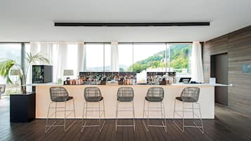 A modern bar area with a long counter, multiple bar stools, and a view of a mountainous landscape through large windows.