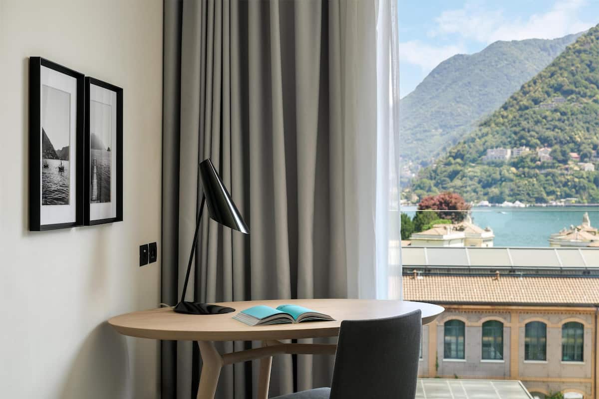 Une pièce avec une table, une lampe et une vue sur un lac et des montagnes.