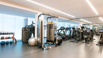 A modern gym with various exercise equipment, including treadmills, ellipticals, and free weights.