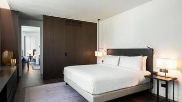 A hotel room with a large bed, bedside lamps, a nightstand, and a view into the hallway.