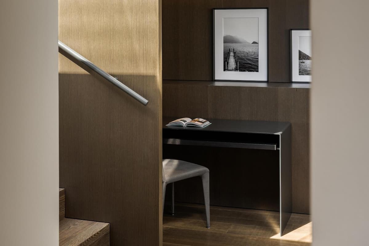 Un intérieur moderne avec un escalier en bois, un bureau avec une chaise et des tableaux encadrés accrochés au mur.