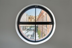A round window with a view of an outdoor seating area and buildings.