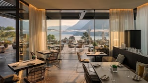 A restaurant with outdoor seating overlooking a mountainous landscape. - Hilton Lake Como (Como)